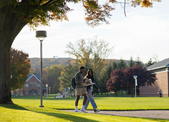 Students smiling and walking on the path through the Quad on the Mount Carmel Campus