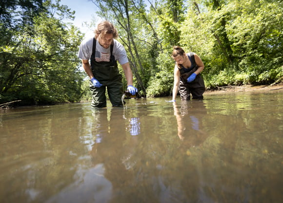 Students stand in the river testing the water