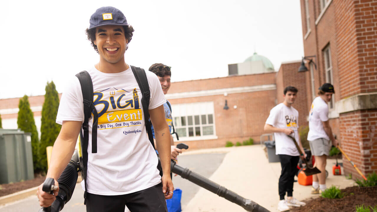 Students smile as they leafblow for Big Event.