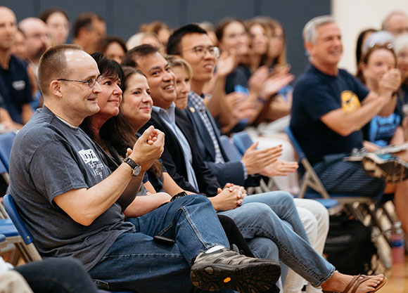 The winners of the Center for Excellence award sit in the front row of chairs and smile and clap