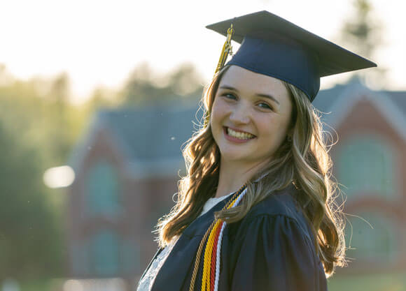 Isabella Foley smiles wearing her graduation cap and gown.