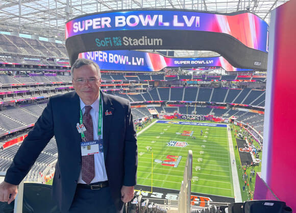 Tim Beach smiles in front of the Superbowl stadium.