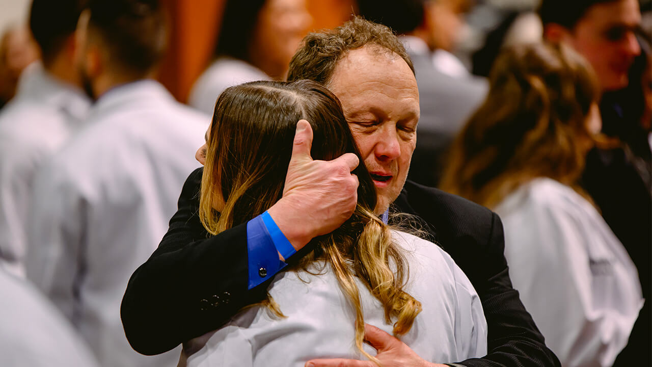 A student is hugged lovingly after the white coat ceremony.