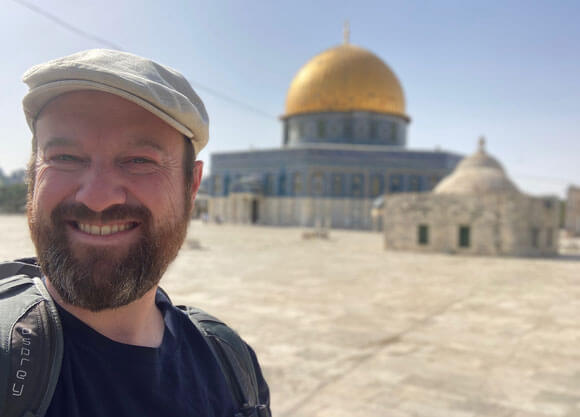 Professor Matthew Rowley takes a selfie in front of a religious building/temple while traveling abroad