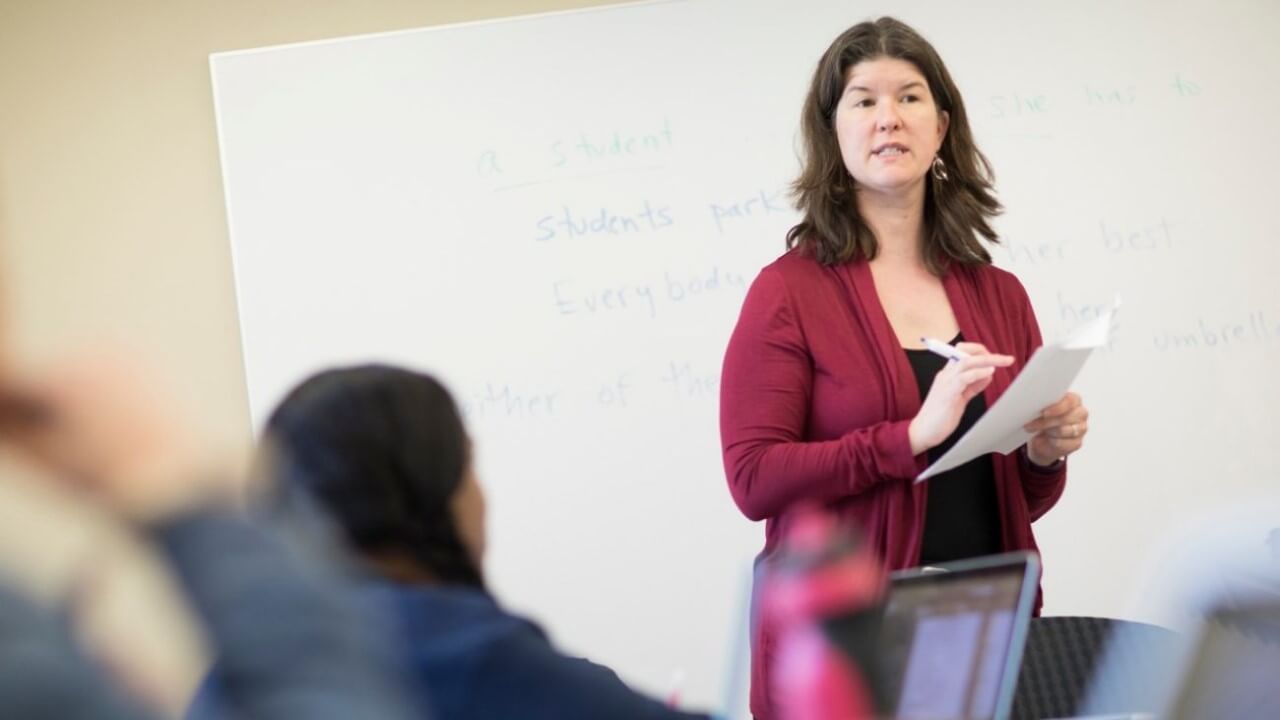 Solomon holds a piece of paper and marker as she speaks in front of a class.