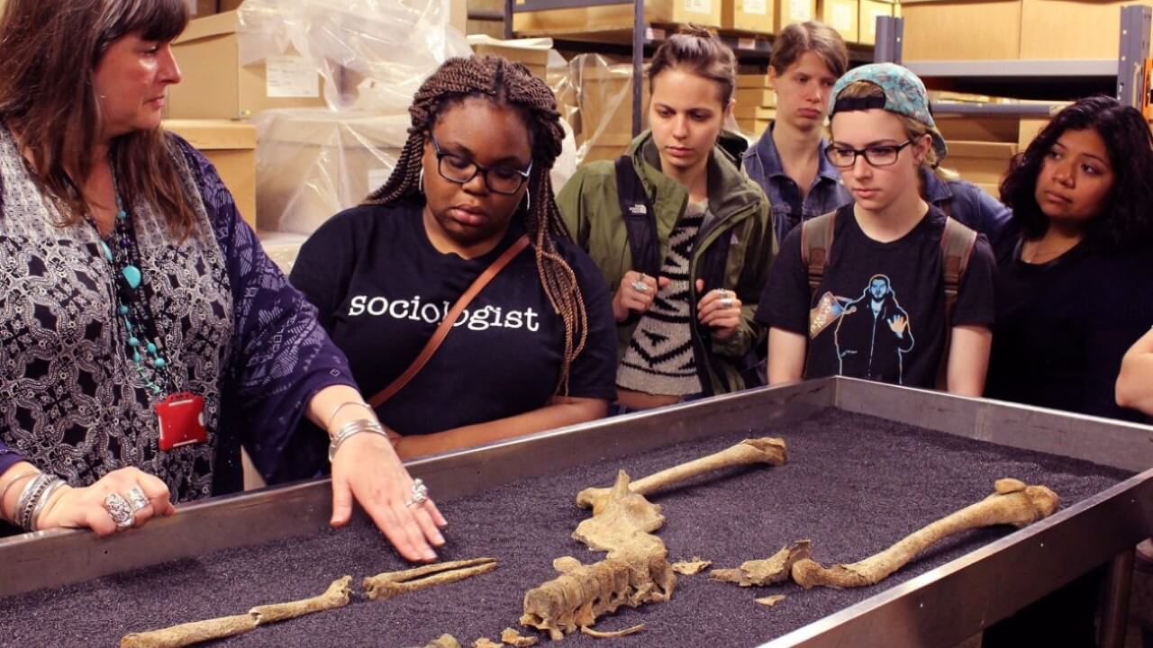 Quinnipiac students study a centuries-old skeleton with the curator at the Museum of London.