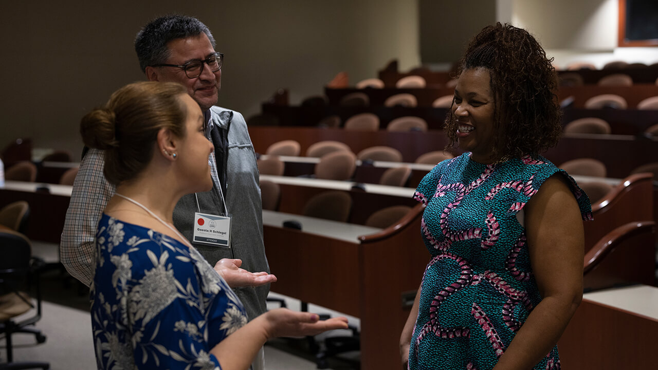 Three people speak during a conference.