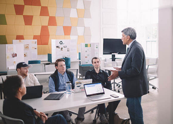 A professor speaks with 4 students inside the Center for Innovation and Entrepreneurship.