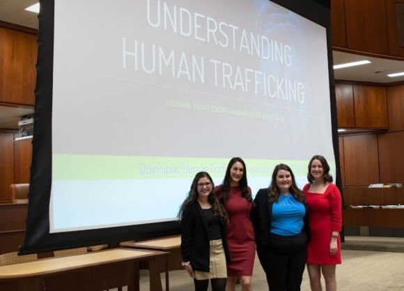 Four women in front of a screen that reads Understanding Human Trafficking