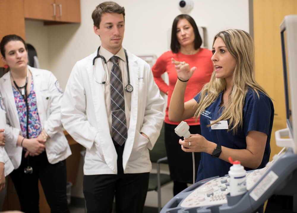 A woman speaking while holding an sonograph wand