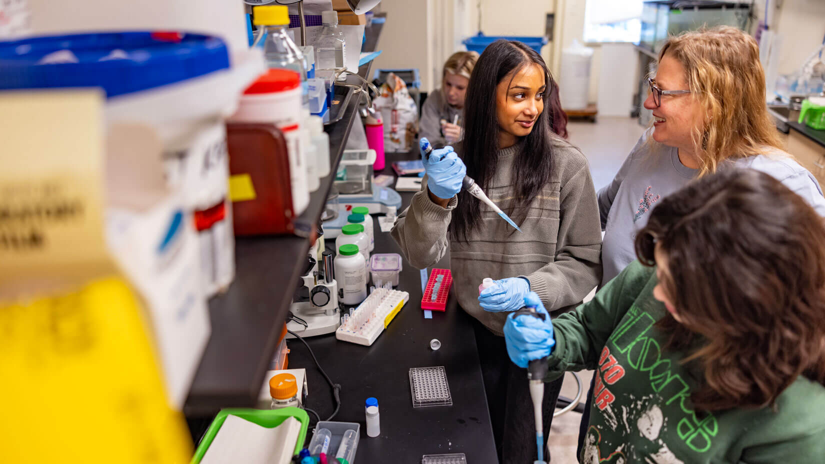 A student receives guidance from a professor during a hands-on lab experiment.