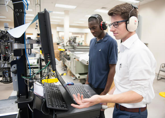 2 men standing at a computer set up