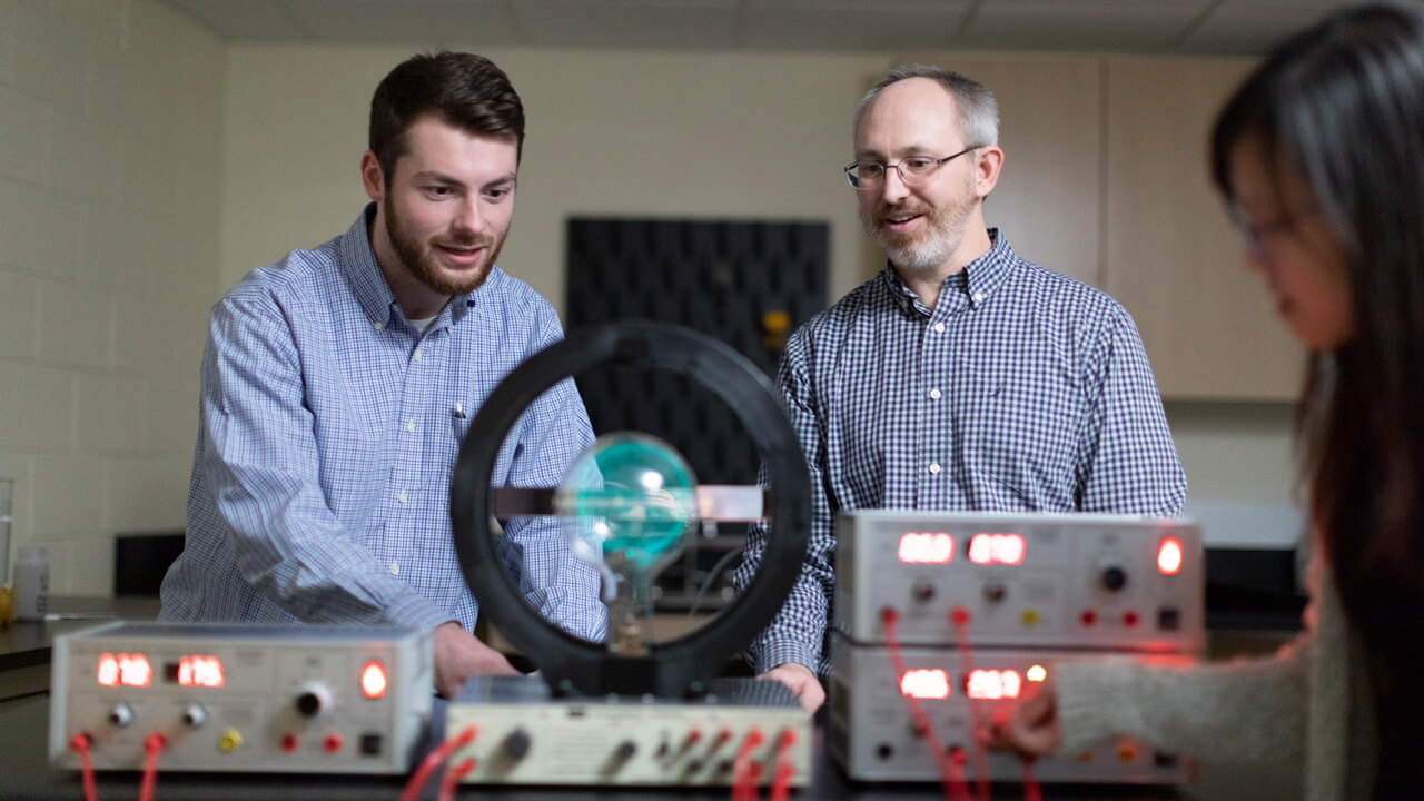 a male student and a professor working with a piece of biochemistry lab equipment