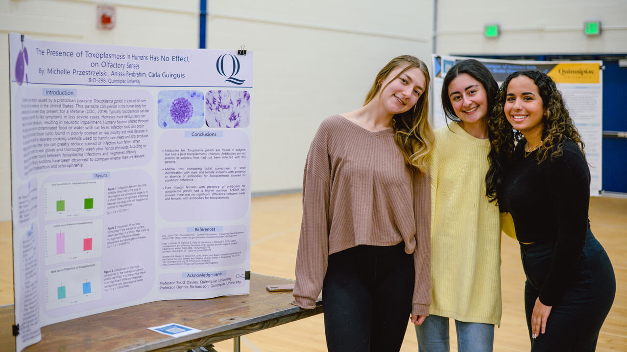 Students pose for a photo in front of their poster project.