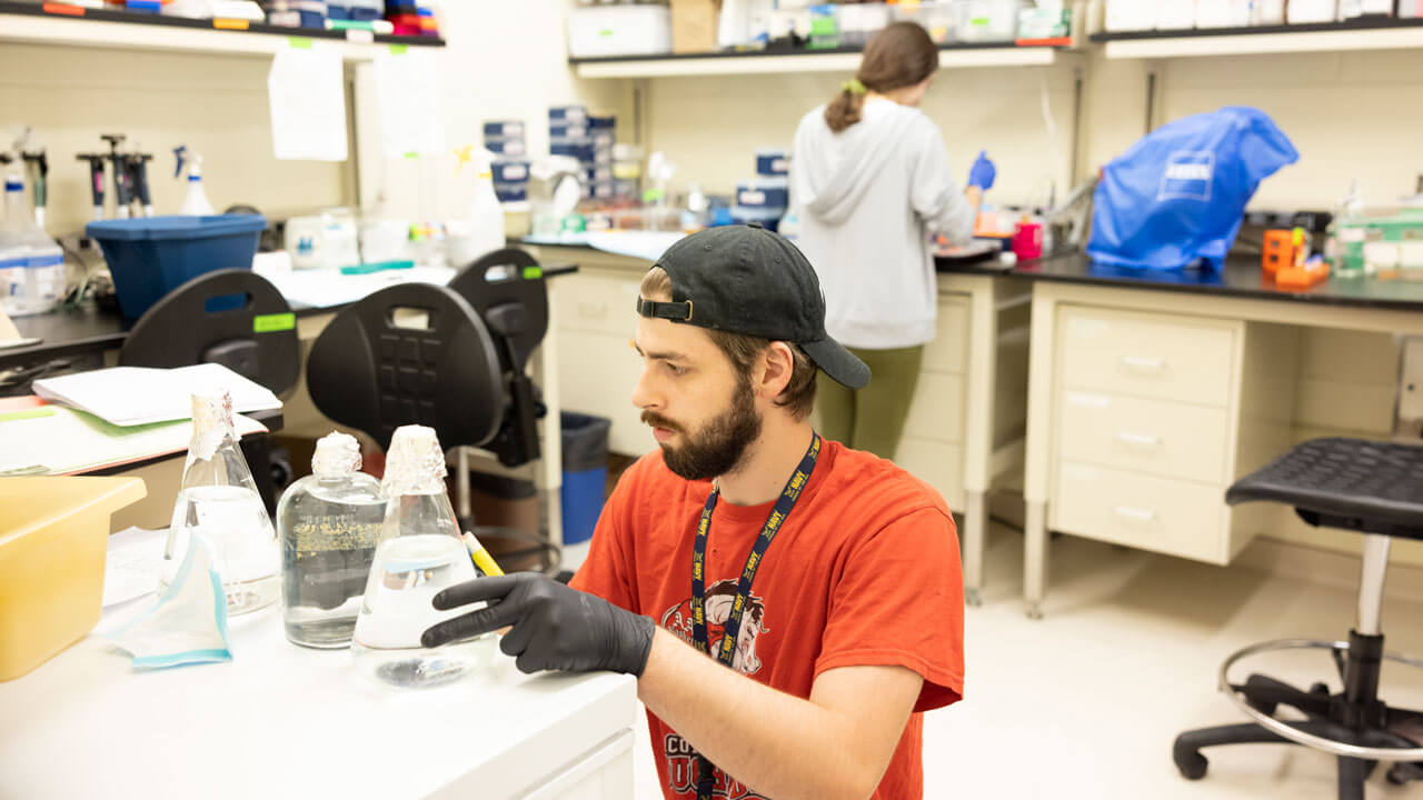 A student analyzes a beaker in a lab.