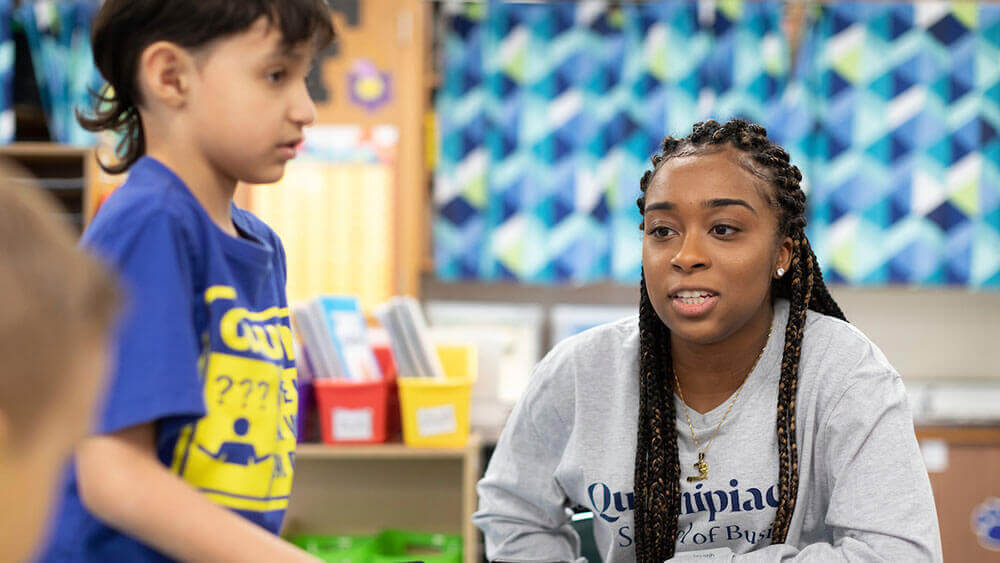 A business student works with an elementary school student