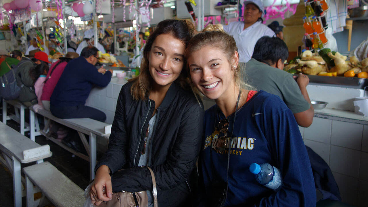 Two students sit in a food market in Peru