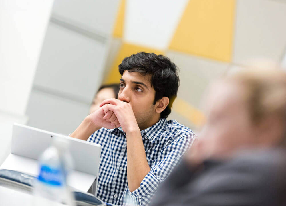 Student sits at desk and listens to a lecture