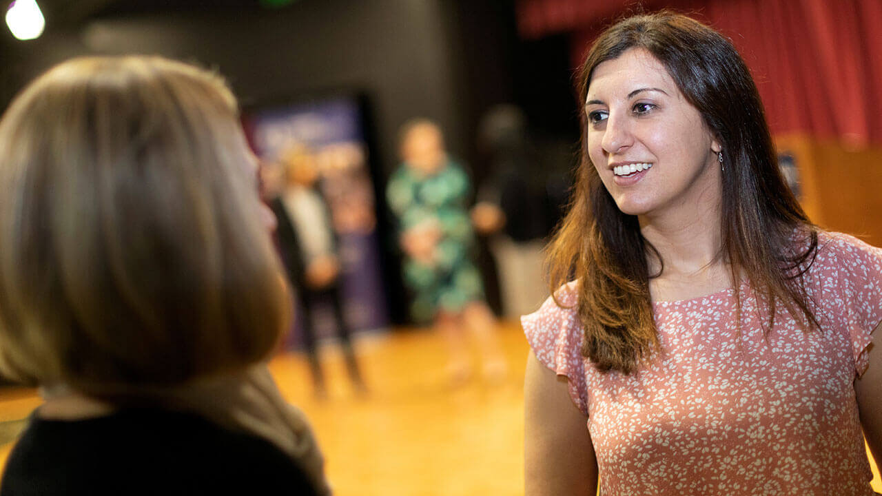 A speaker talks with a student after a lecture