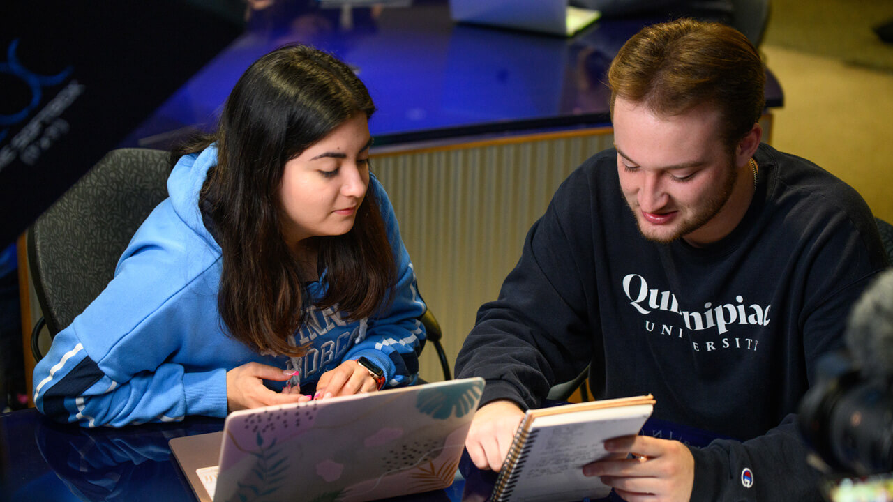 2 students work together with a laptop and a notepad