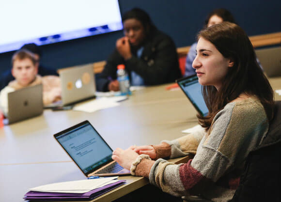 Several students work at laptops in the communications writers' room.