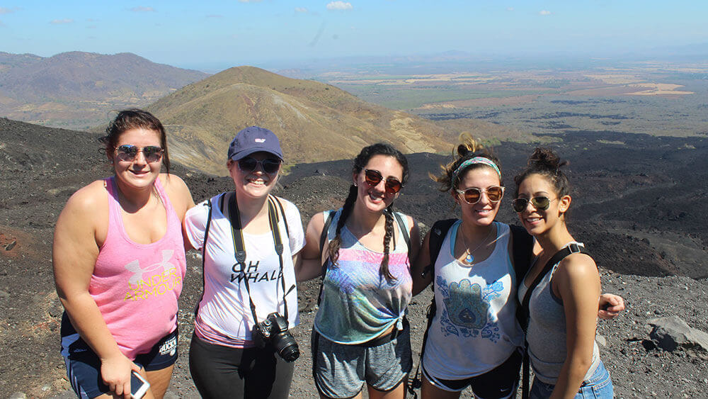 A group of journalism students pose in front of a Nicaraguan mountain range