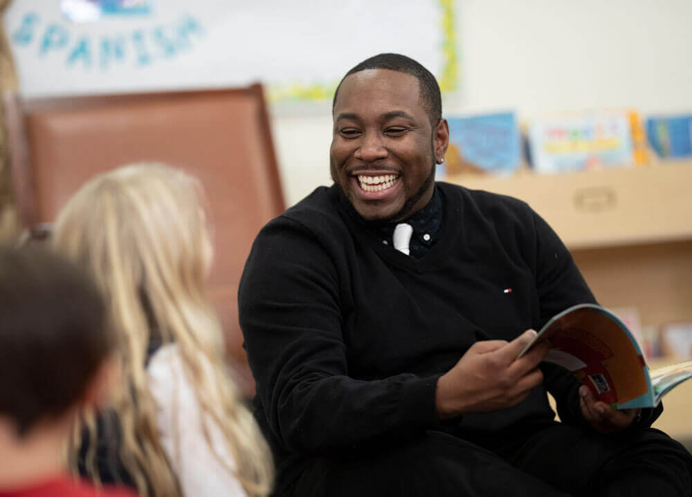 An education student reads a book to children