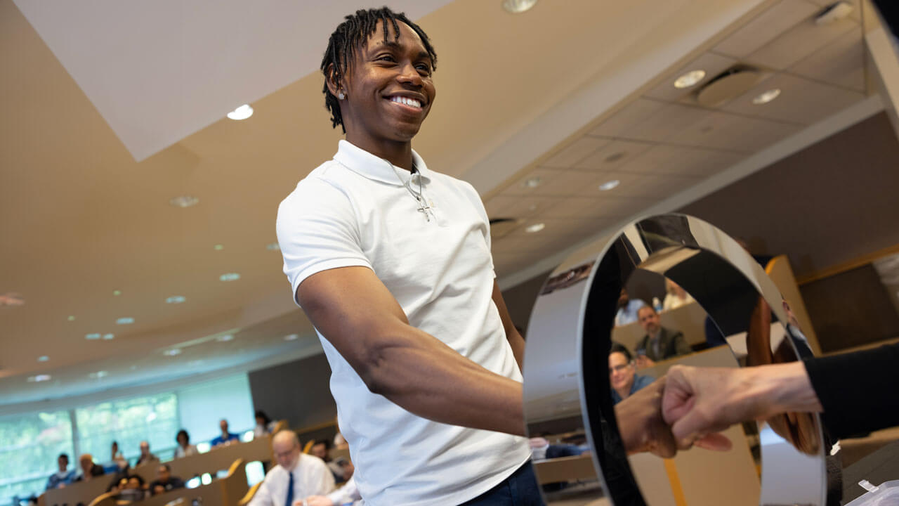 A student smiles, accepting his induction.