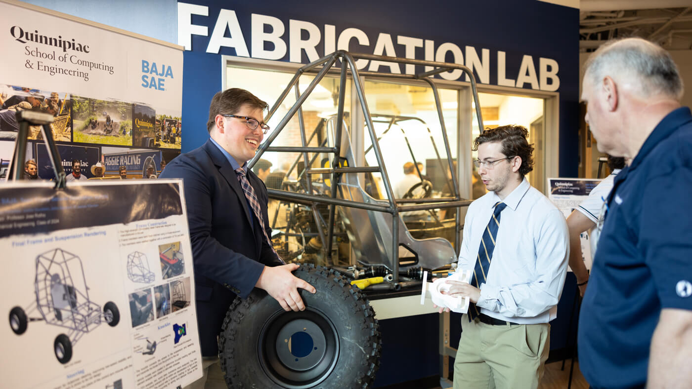 A student shows a tire for the baja project car.