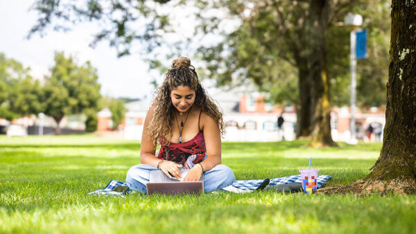 Student works on her computer outside the Arnold Bernhard Library on the Mount Carmel Campus.