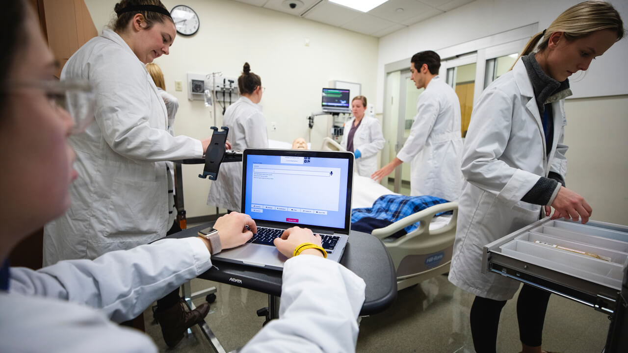 A person works on a computer in a healthcare simulation room