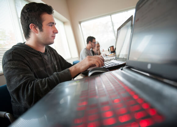 Student typing at his laptop during class.