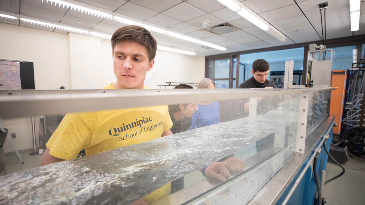 A student in the Fluids lab standing next to the Hydraulic Demonstration Channel