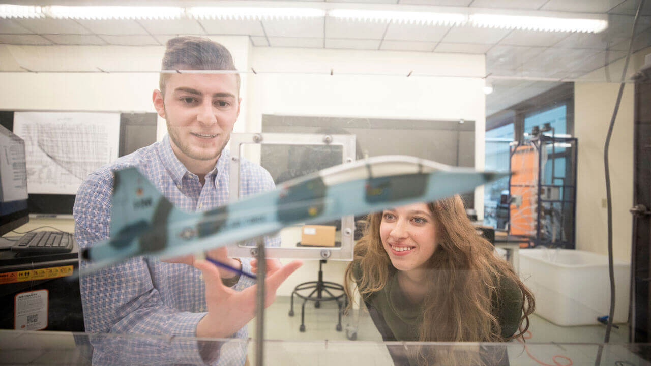 Two students using the School of Engineering's areodynamics simulation chamber