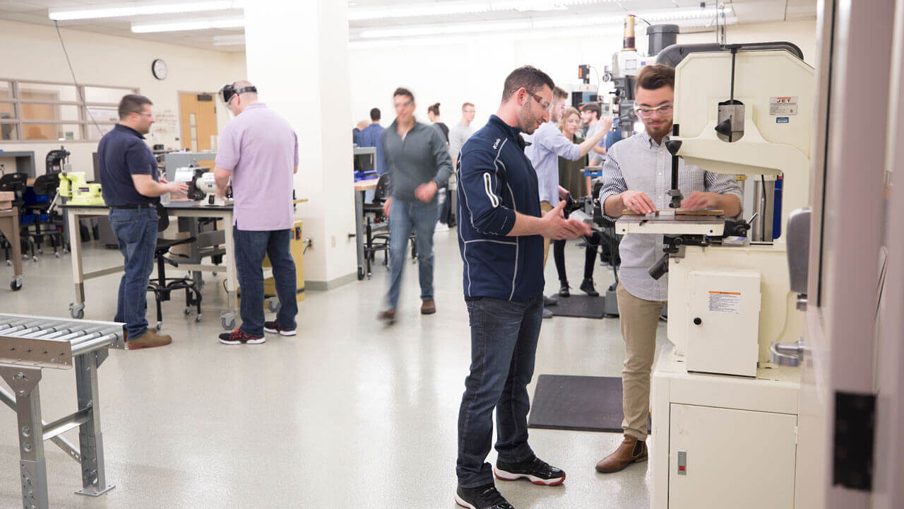 A group of students working with various machinery and technology in a classroom