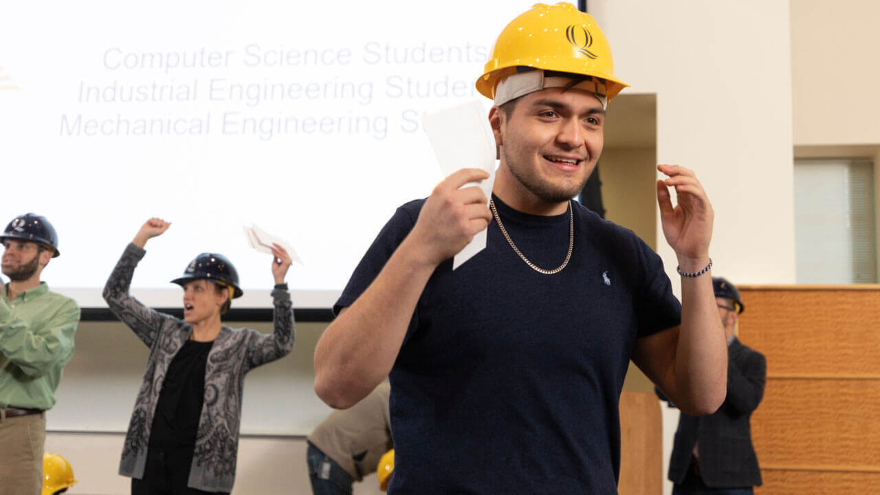 Student smiling while wearing Quinnipiac-branded hard hat