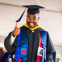 Donald Claude walking across stage in his cap and gown at commencement