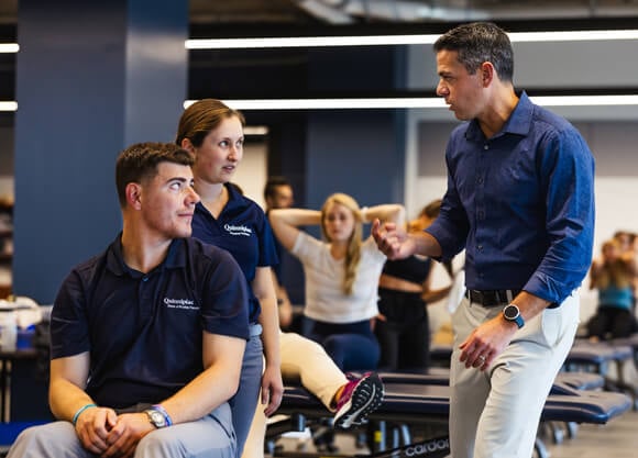 Professor gives instruction to students performing a hands-on demonstration.