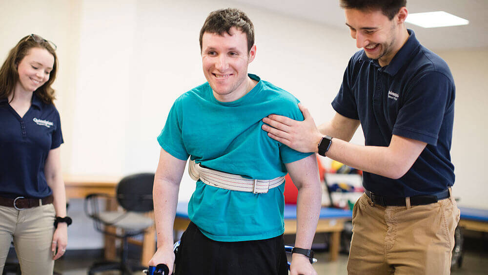 Two health sciences students assist a patient with his crutches