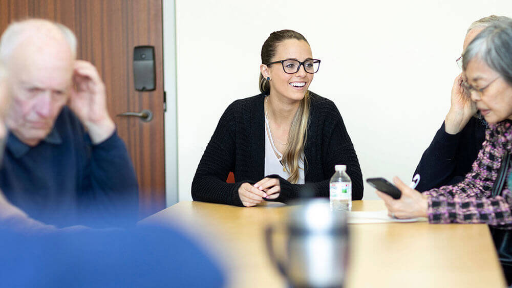 A social work student leads a group of seniors in a low vision clinic