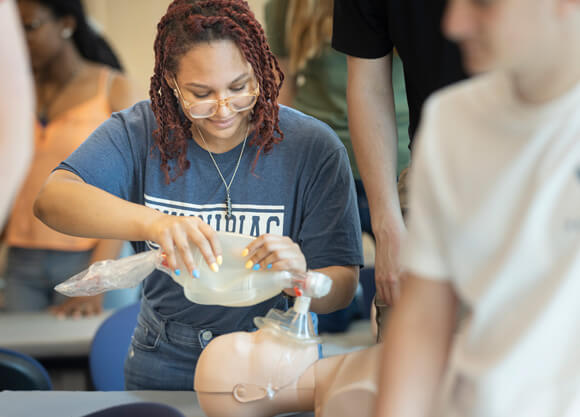 A female student using a bag valve mask on a mannikin