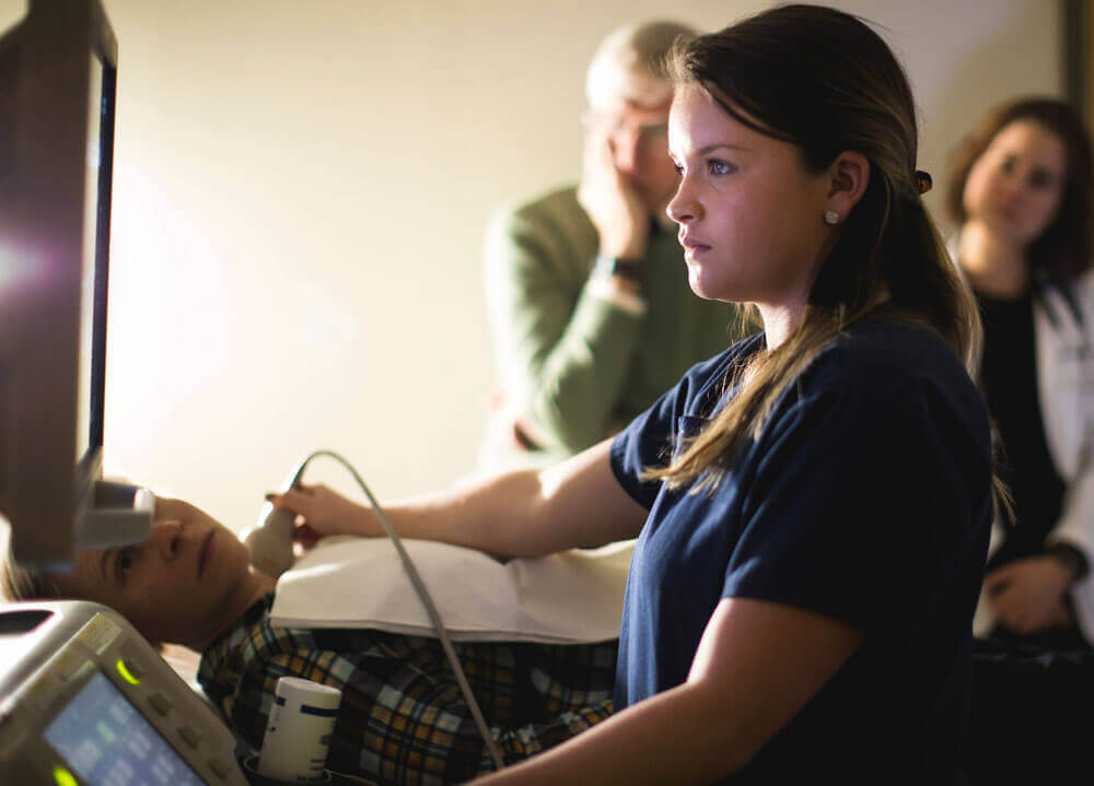 A student demonstrates how to use the cardiac ultrasound to a group of medical students