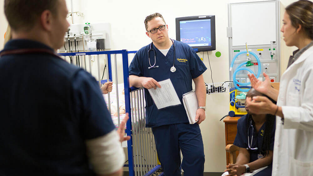 A nursing student stands in a pediatrician's office listening to her advice