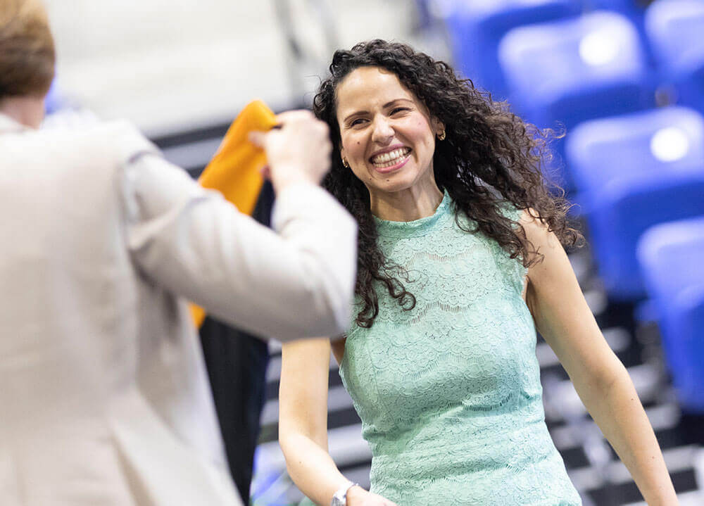 A nursing student receives her hood from a professor for an upcoming commencement ceremony