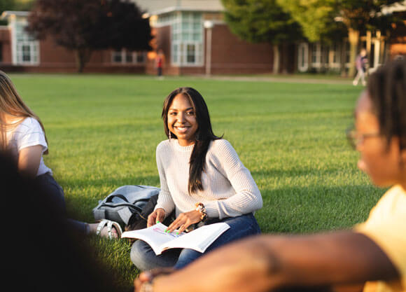 Two students sit in the lawn of the quad