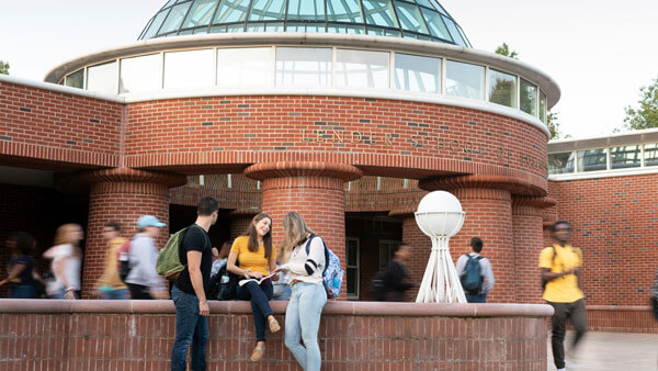 Dozens of students walk and talk outside the School of Business Center.