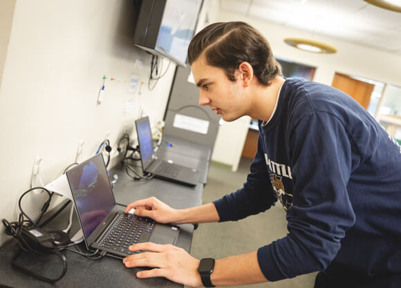 Student worker at a laptop in an office.