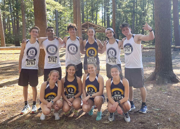 Members of the club running team in their uniforms smile together in Sleeping Giant State Park