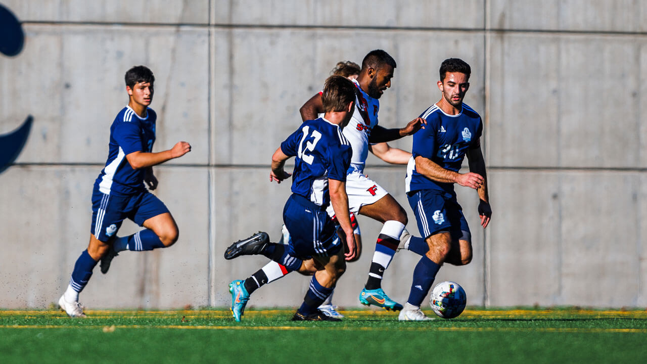 Men attempting to steal soccer ball from opposing team