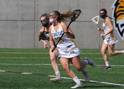 3 women running across lacrosse field